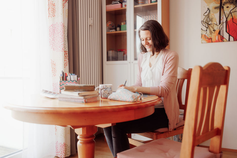 Janina Steger sitzt am Tisch und malt; Foto von Daniel Stein